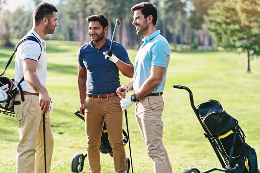 Three golfers chatting on the golf course between shots.